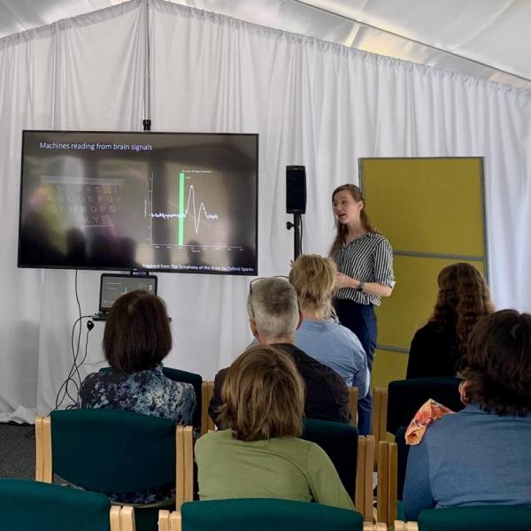 Demi stands in front of an audience at a science festival.