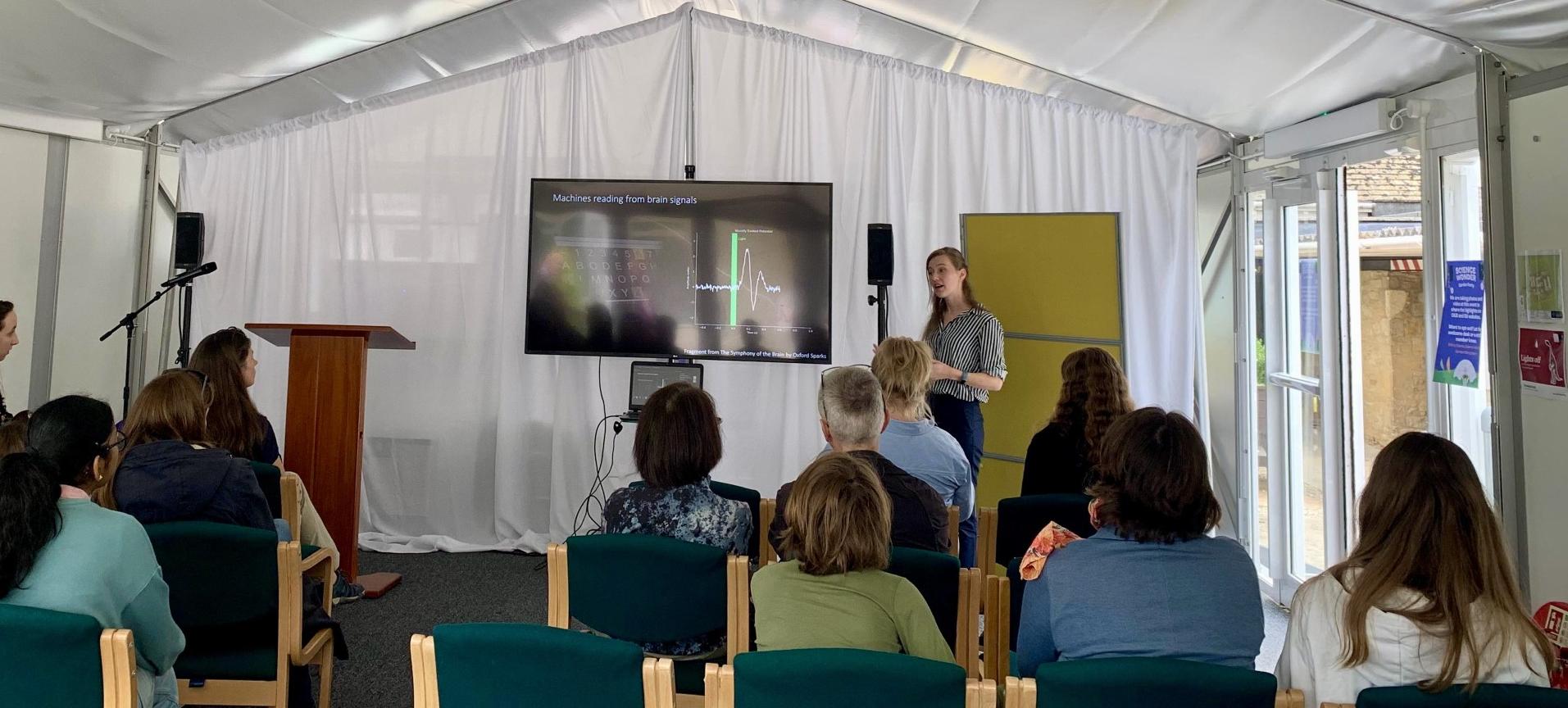 Demi stands in front of an audience at a science festival.