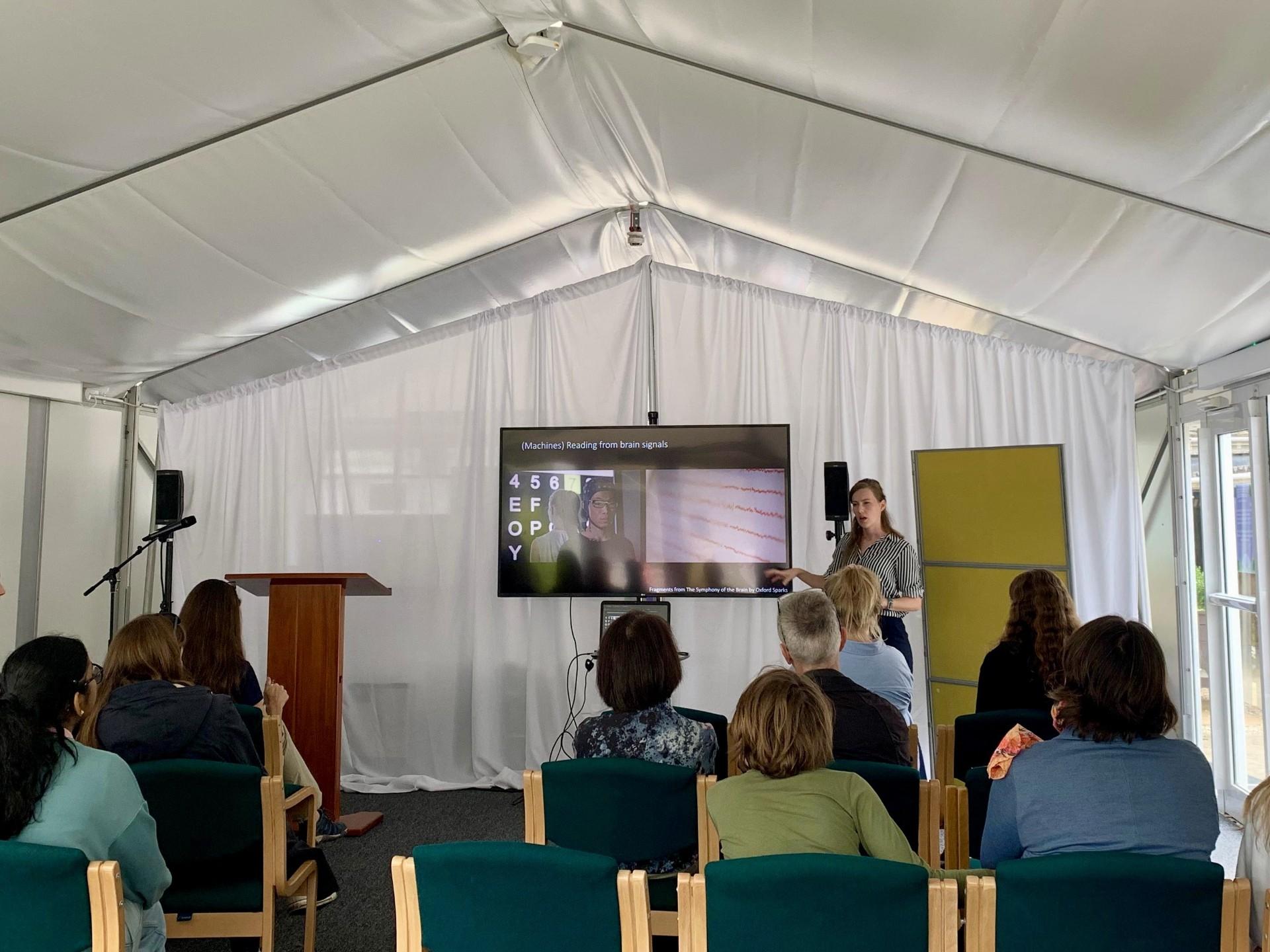 Demi stands in front of an audience at a science festival.