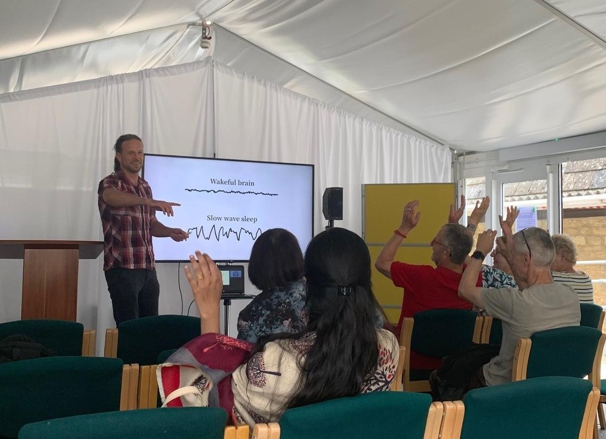 A smiling Joram interacting with the audience, selecting from those with raised hands.