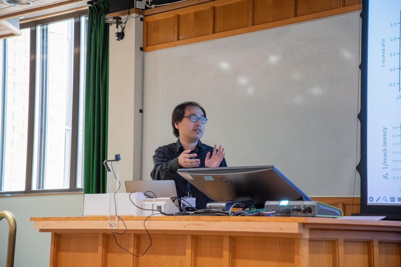 A photo of Teris Tam presenting his research to Unit colleagues.