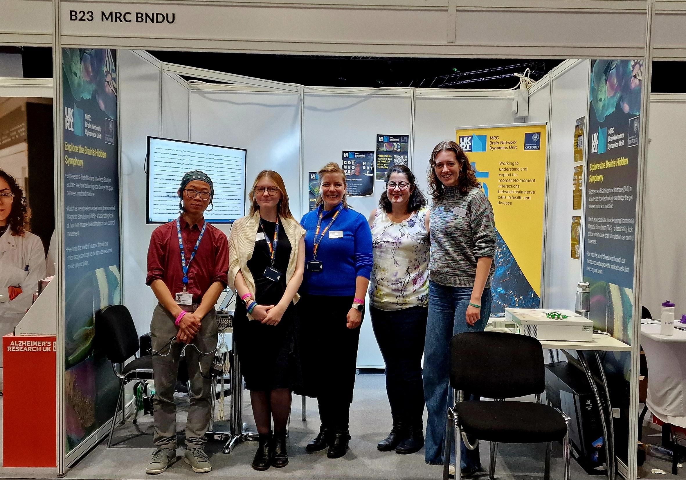 four people stand in front of the stand
