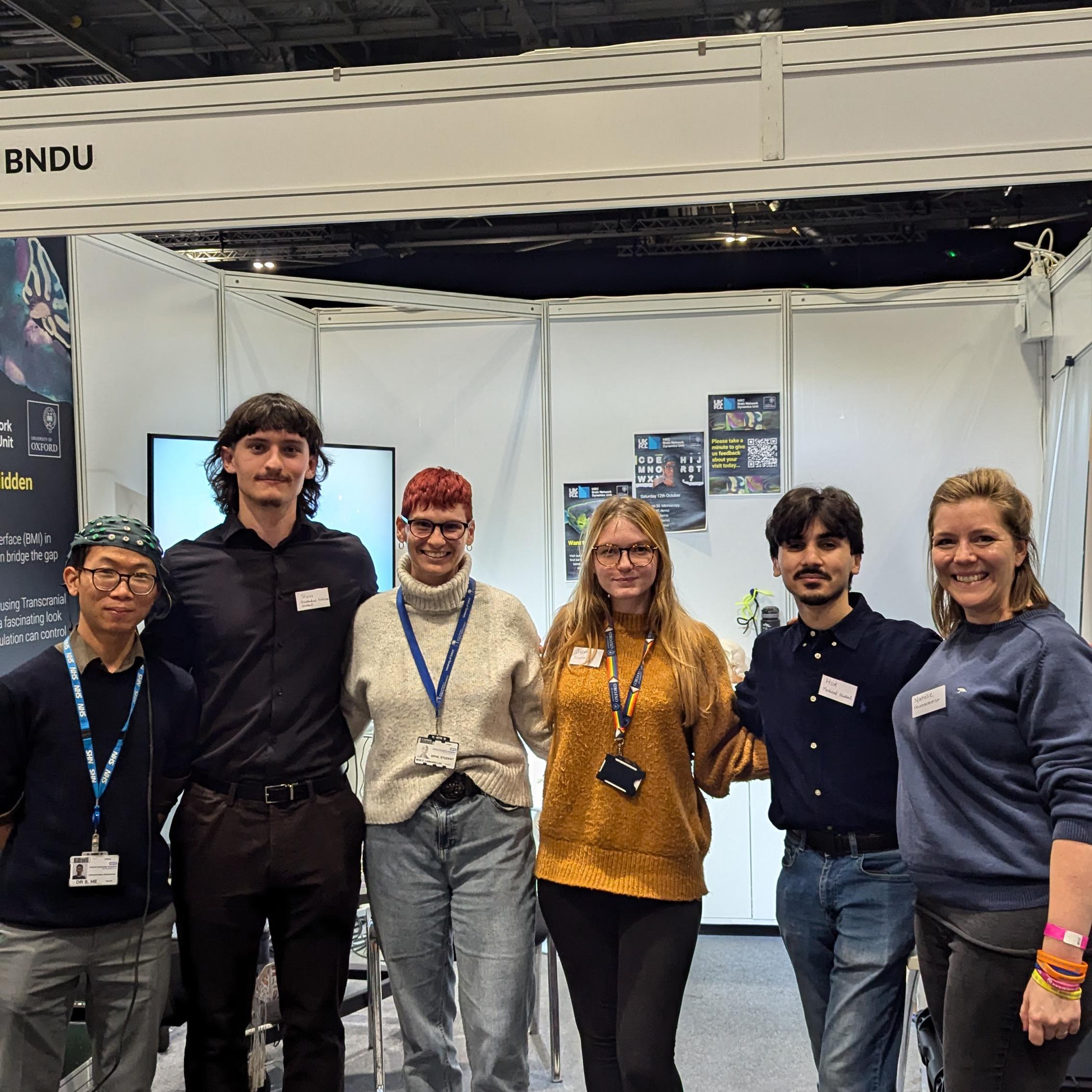 a group photo of people in front of the stand